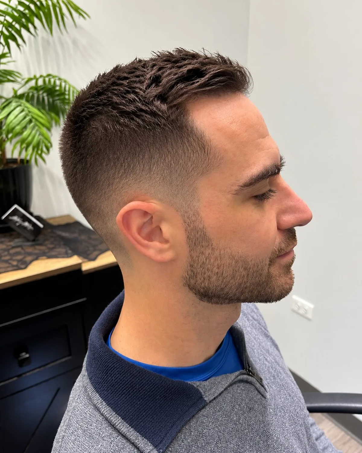 Short dark haircut with a textured top and close fade, side view